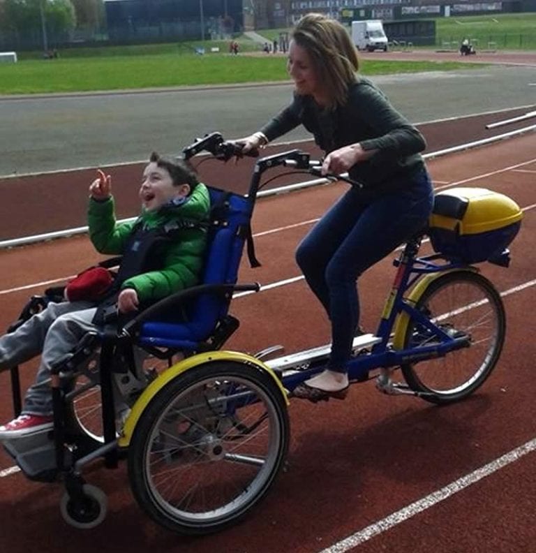 Child on an accessible bike smiling with his mother